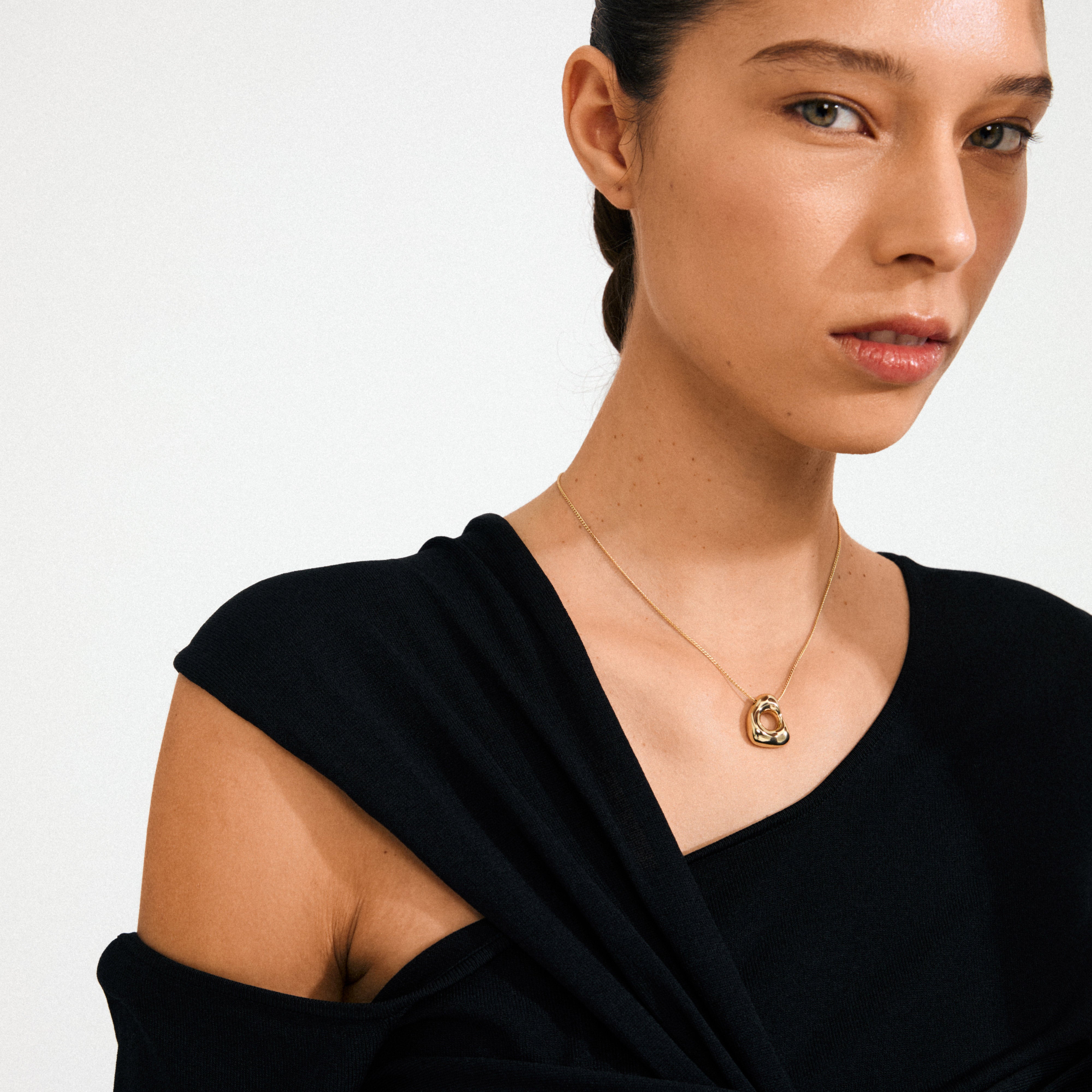 Young woman wearing Pilgrim's FREE necklace gold-plated, featuring an interlocking circular pendant on a slender chain, embodying natural elegance and Scandinavian craftsmanship.