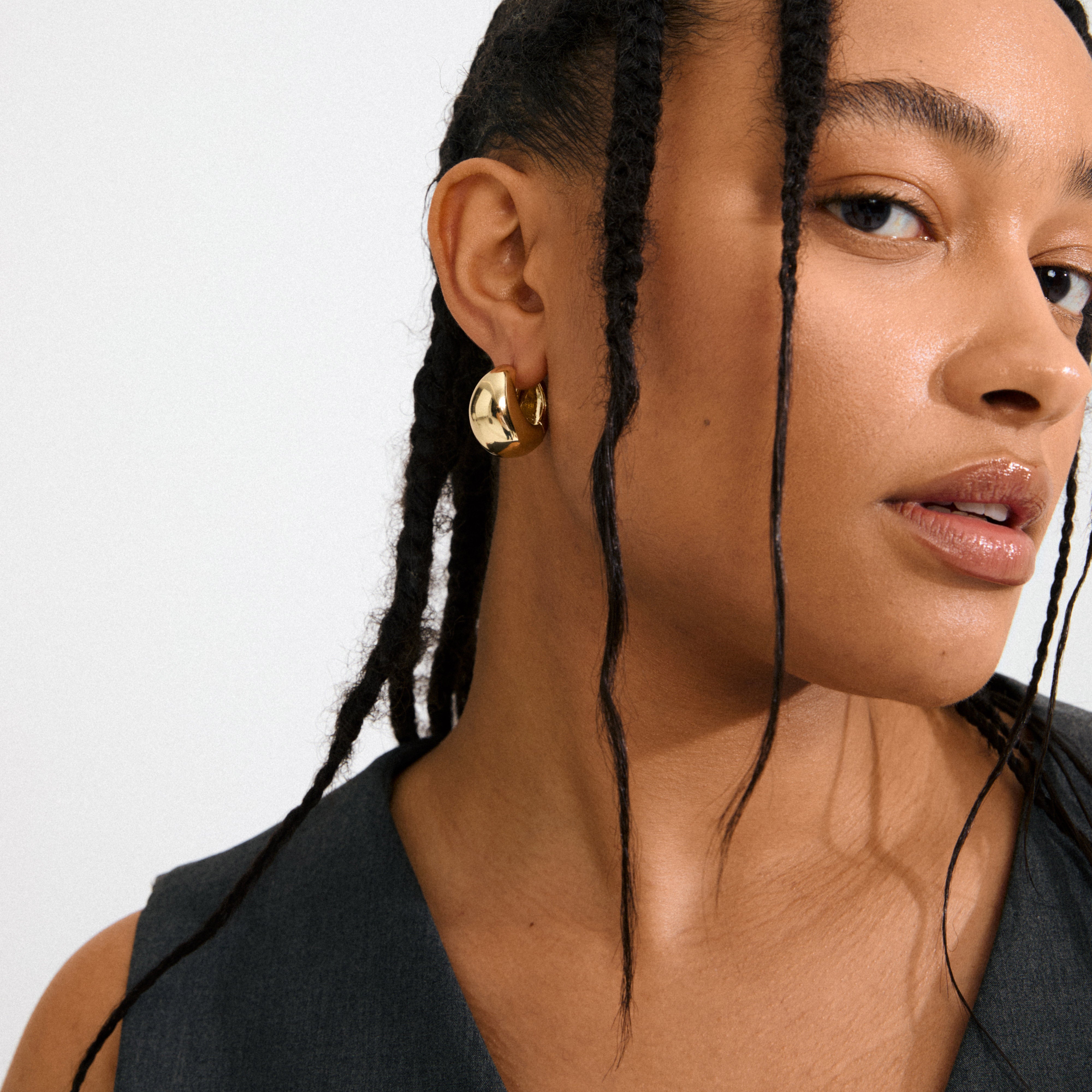 Medium-brown skin with long braids wearing Pilgrim's FREE hoops gold-plated; chunky, uneven design adds edgy elegance.