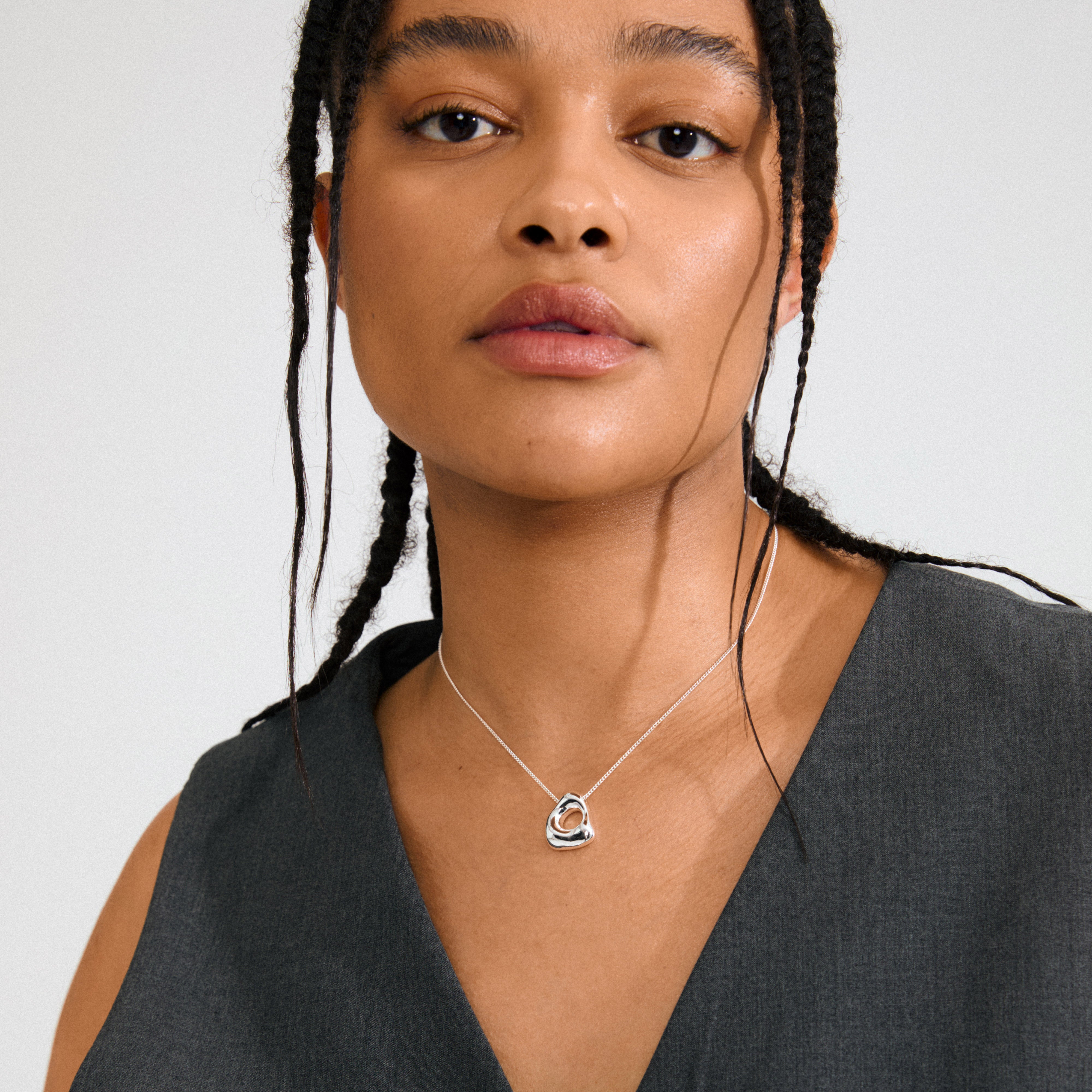 Young woman wears Pilgrim's FREE necklace, featuring a silver-plated, sculptural pendant on a delicate chain, embodying nature-inspired elegance and Scandinavian craftsmanship.