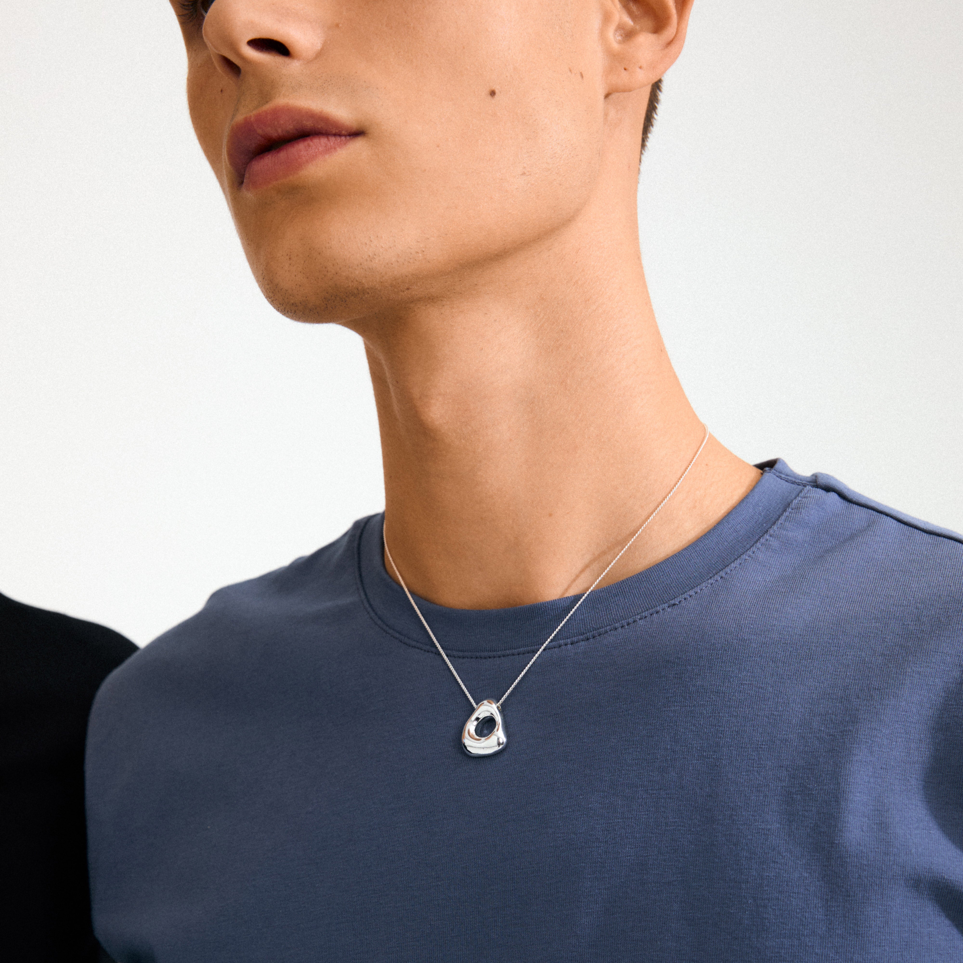 Person wearing the FREE necklace silver-plated by Pilgrim, featuring a sculptural, ocean-inspired silver pendant on a fine chain, embodying nature's elegance and eco-conscious design.
