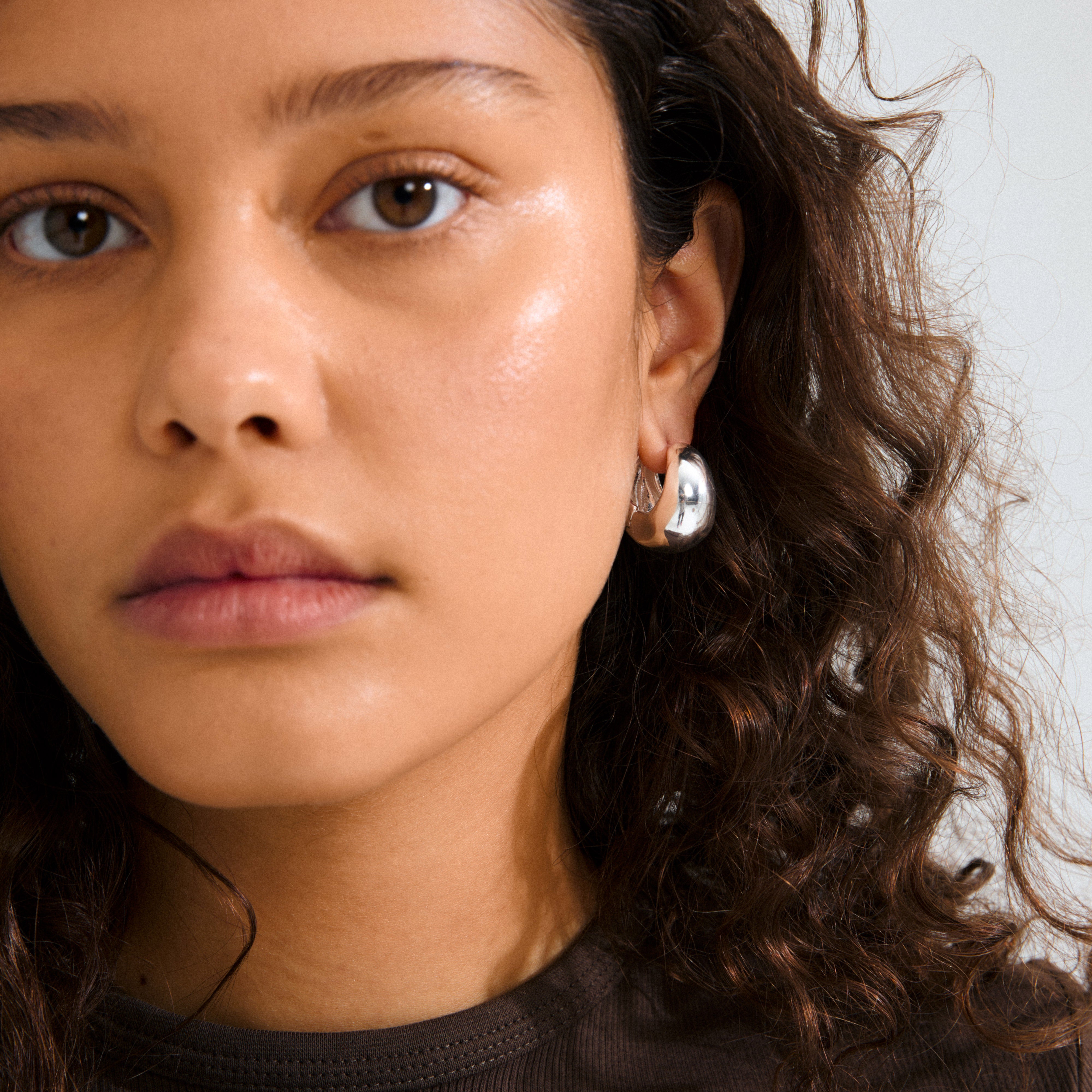 Young person wearing Pilgrim's FREE hoops silver-plated earring, showcasing a chunky, polished design that adds an edgy, chic touch to their look.