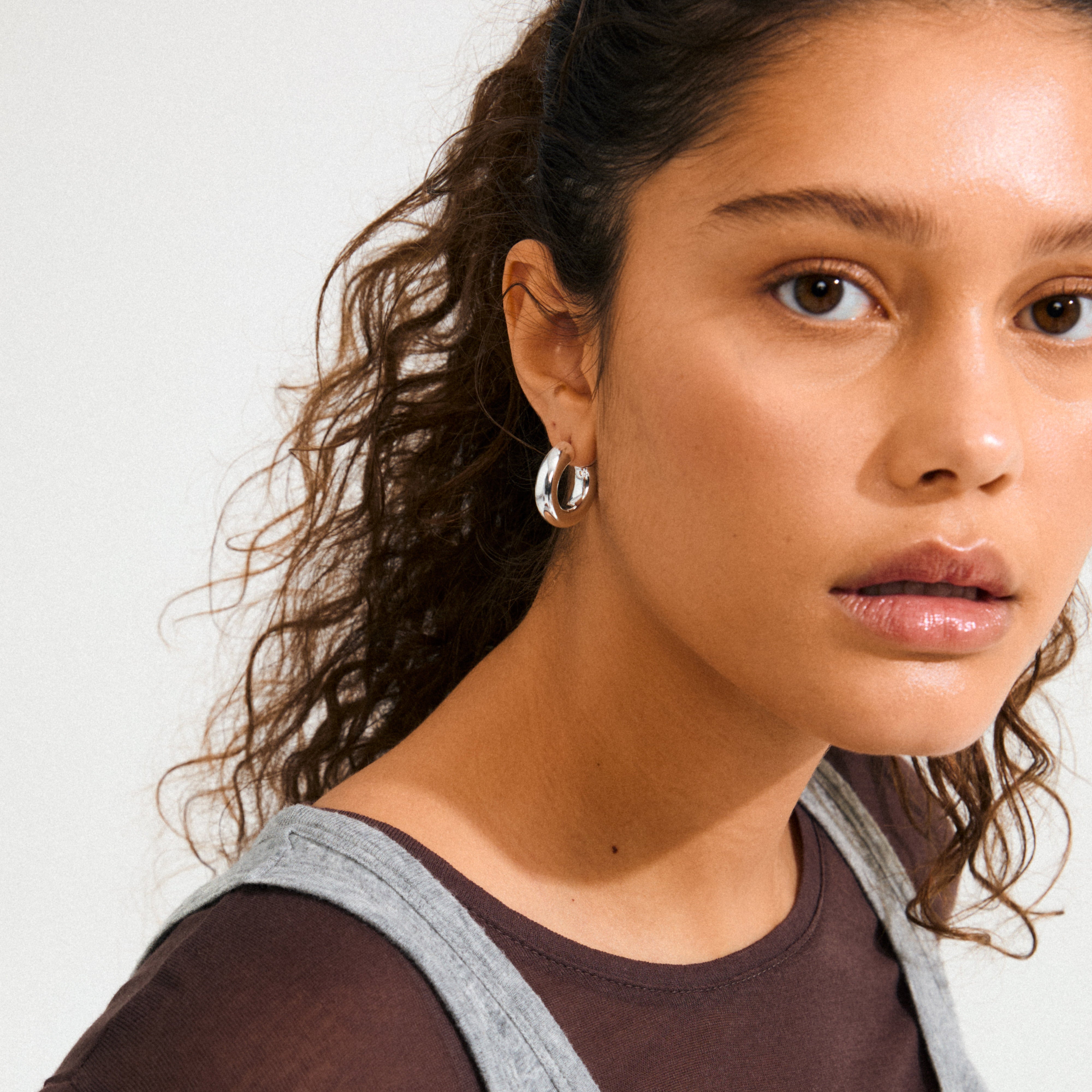 Young person wearing Pilgrim's PHASE medium hoops, silver-plated, showcasing chunky, polished design. Ideal for a refined, stylish look with subtle luxury.