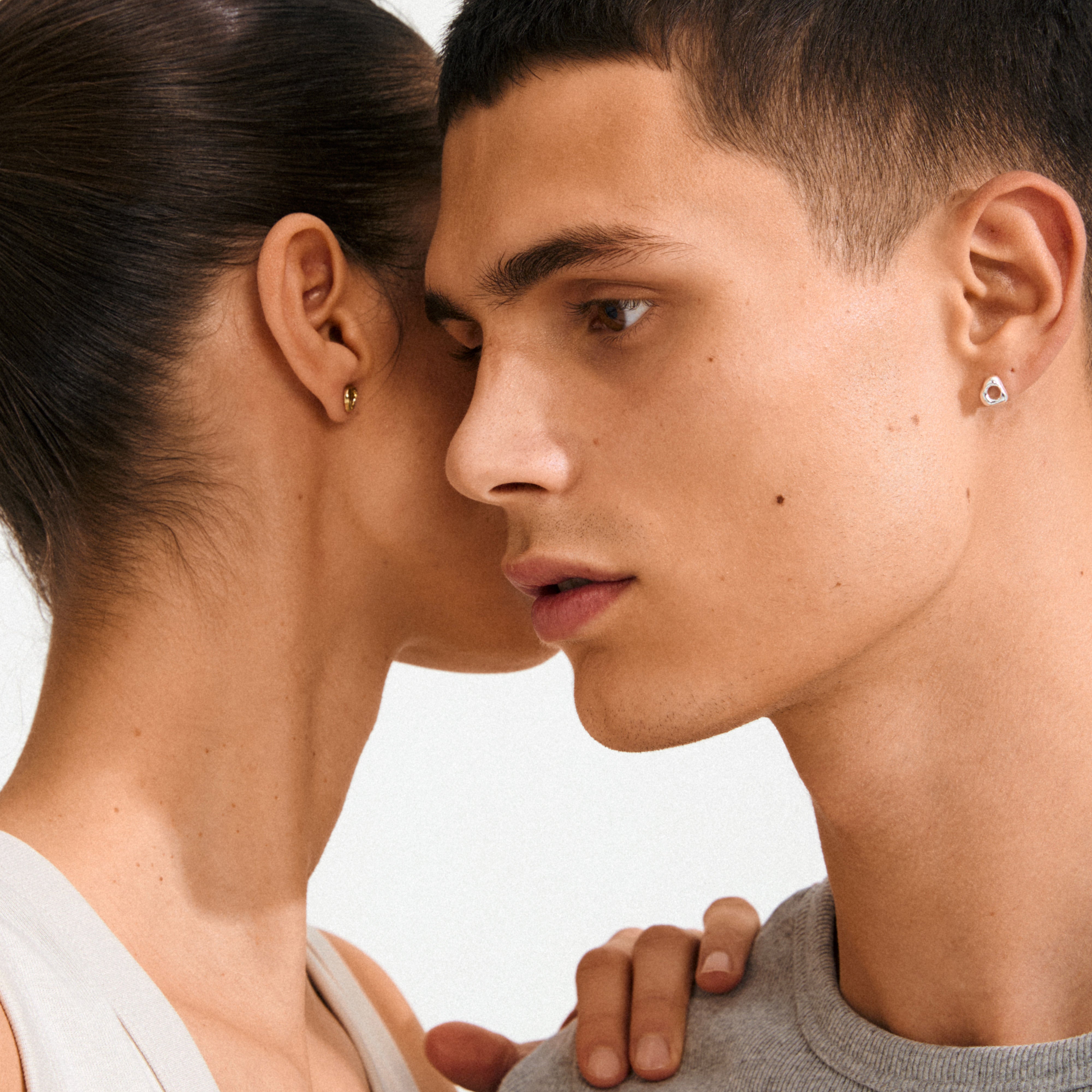 Two people wearing Pilgrim's FREE gold-plated stud earrings, designed with an organic shape, highlighting simplicity and natural elegance.