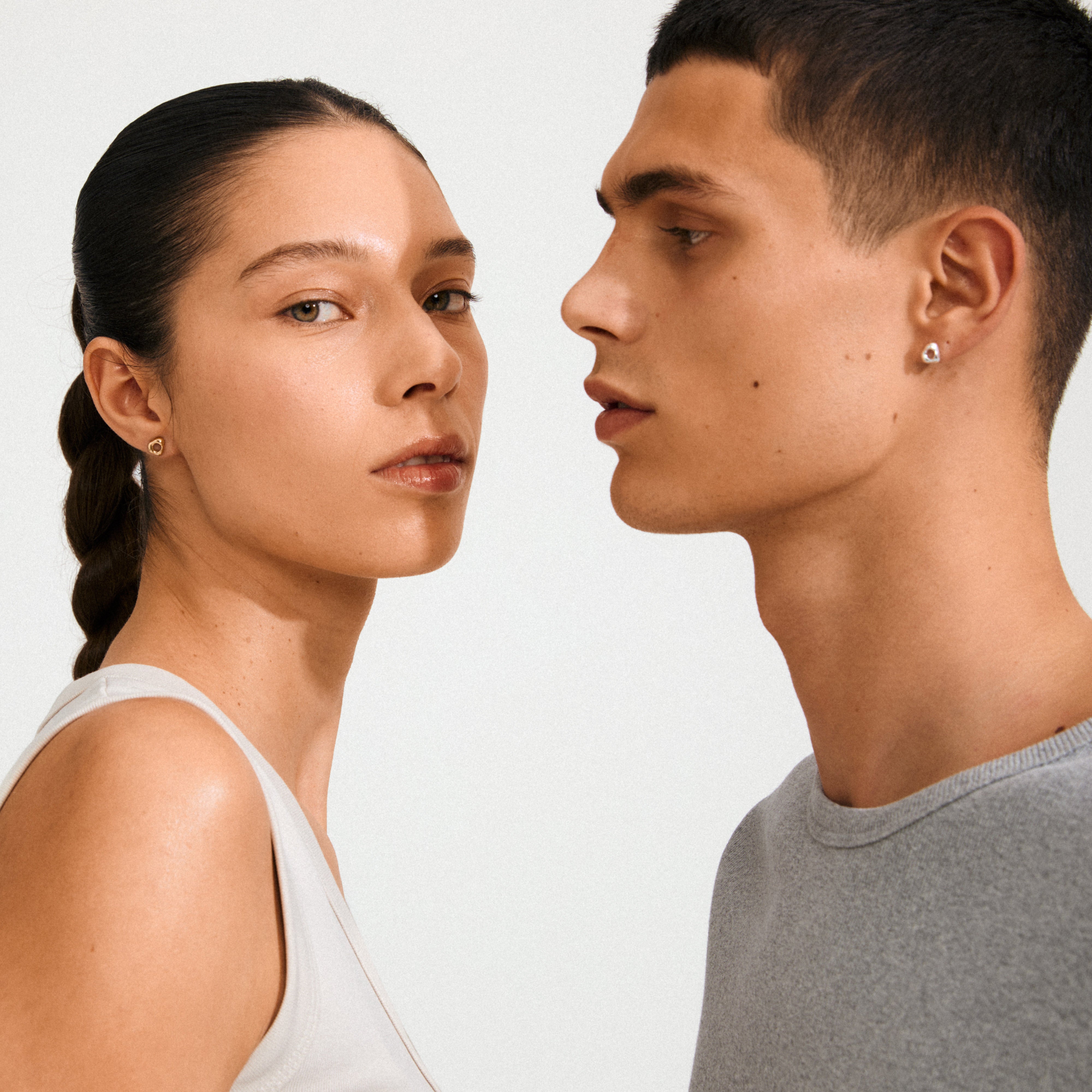 Two young adults showcasing Pilgrim's FREE gold-plated stud earrings, highlighting their organic, minimalist design inspired by hagstones for everyday style.