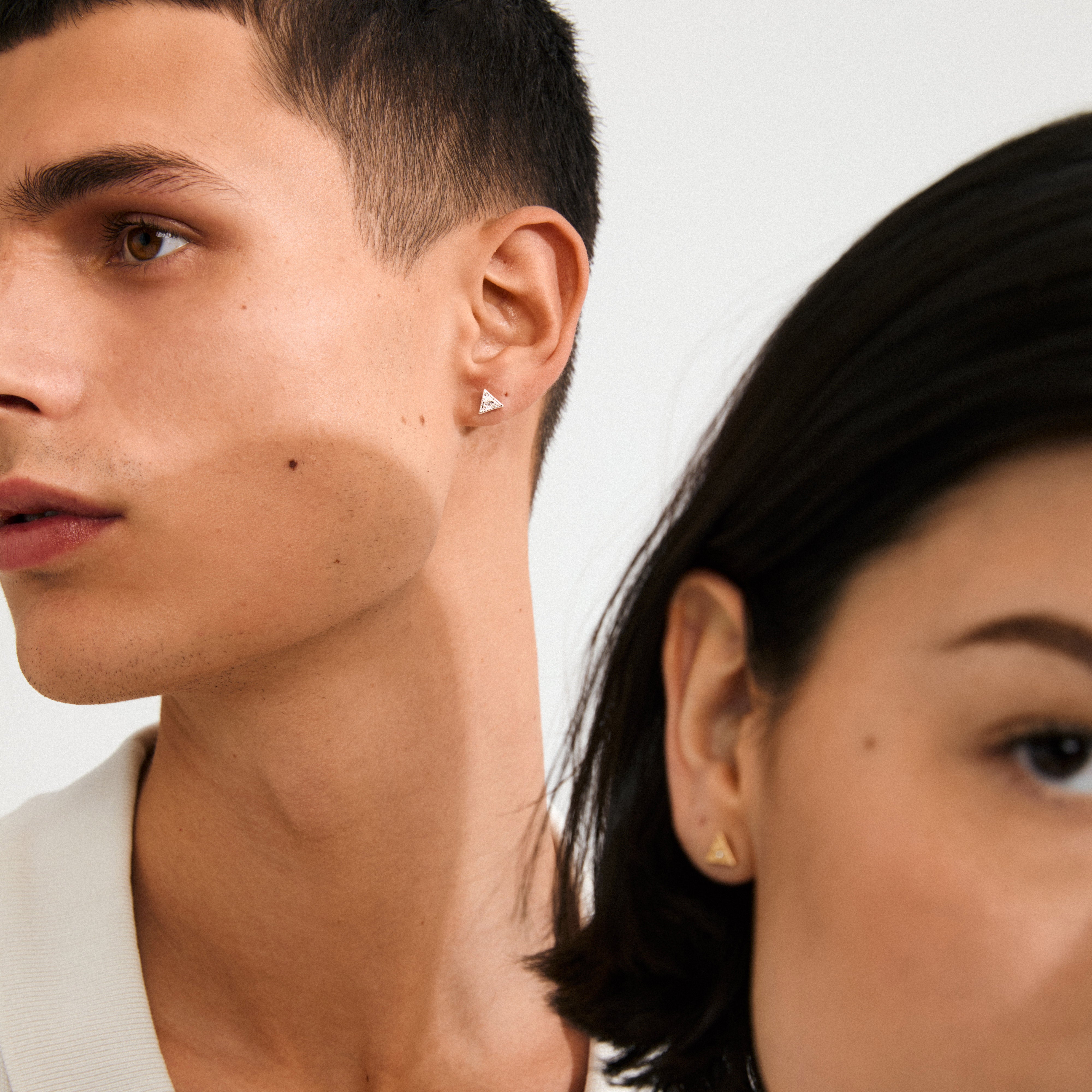 Two young adults model Pilgrim's gold-plated RYLEE triangle stud earrings, showcasing a minimalist, boho chic design perfect for an ear stack.
