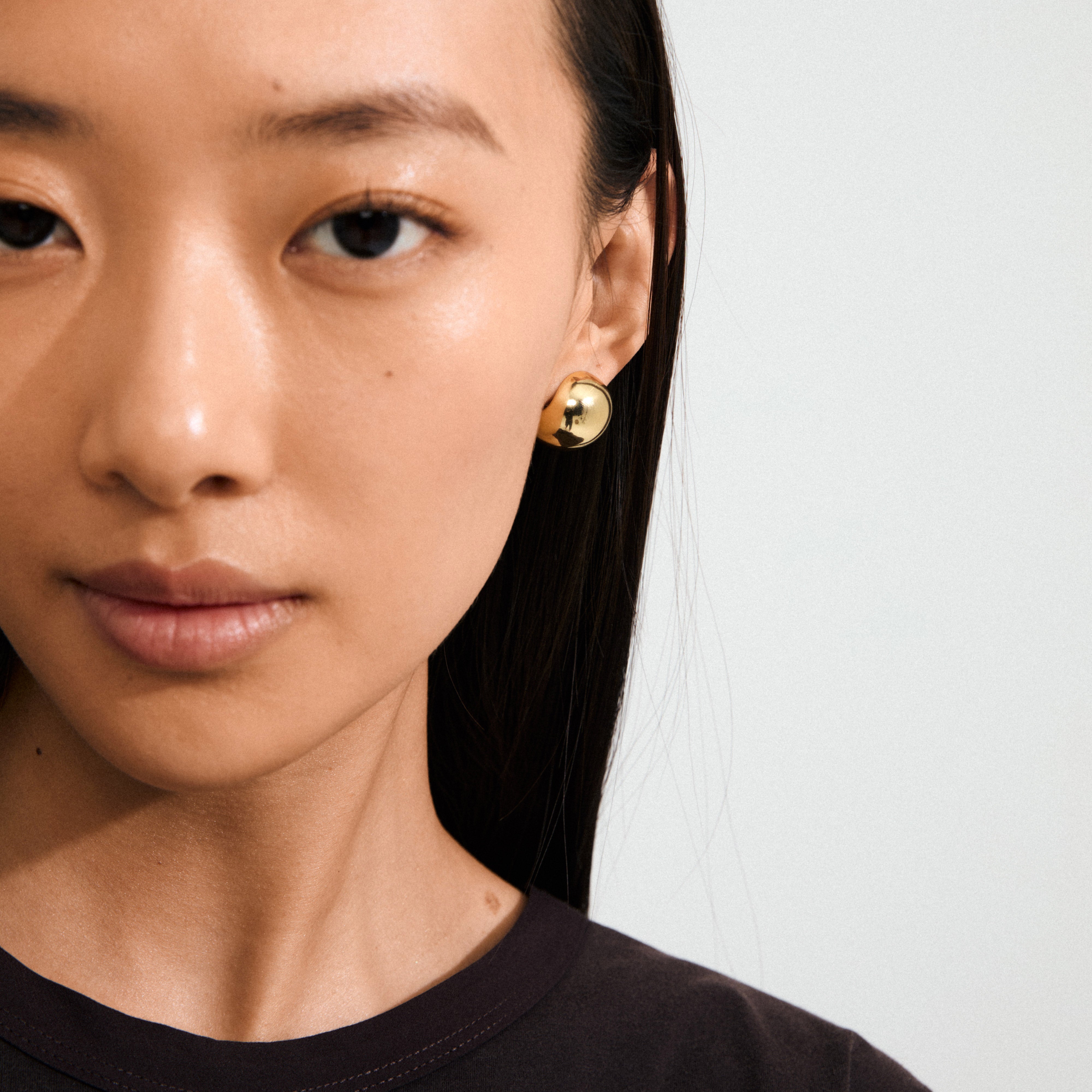 Young woman wearing a Pilgrim's JACE gold-plated earring with a shiny bubble dome design, showcasing a retro, stylish look.