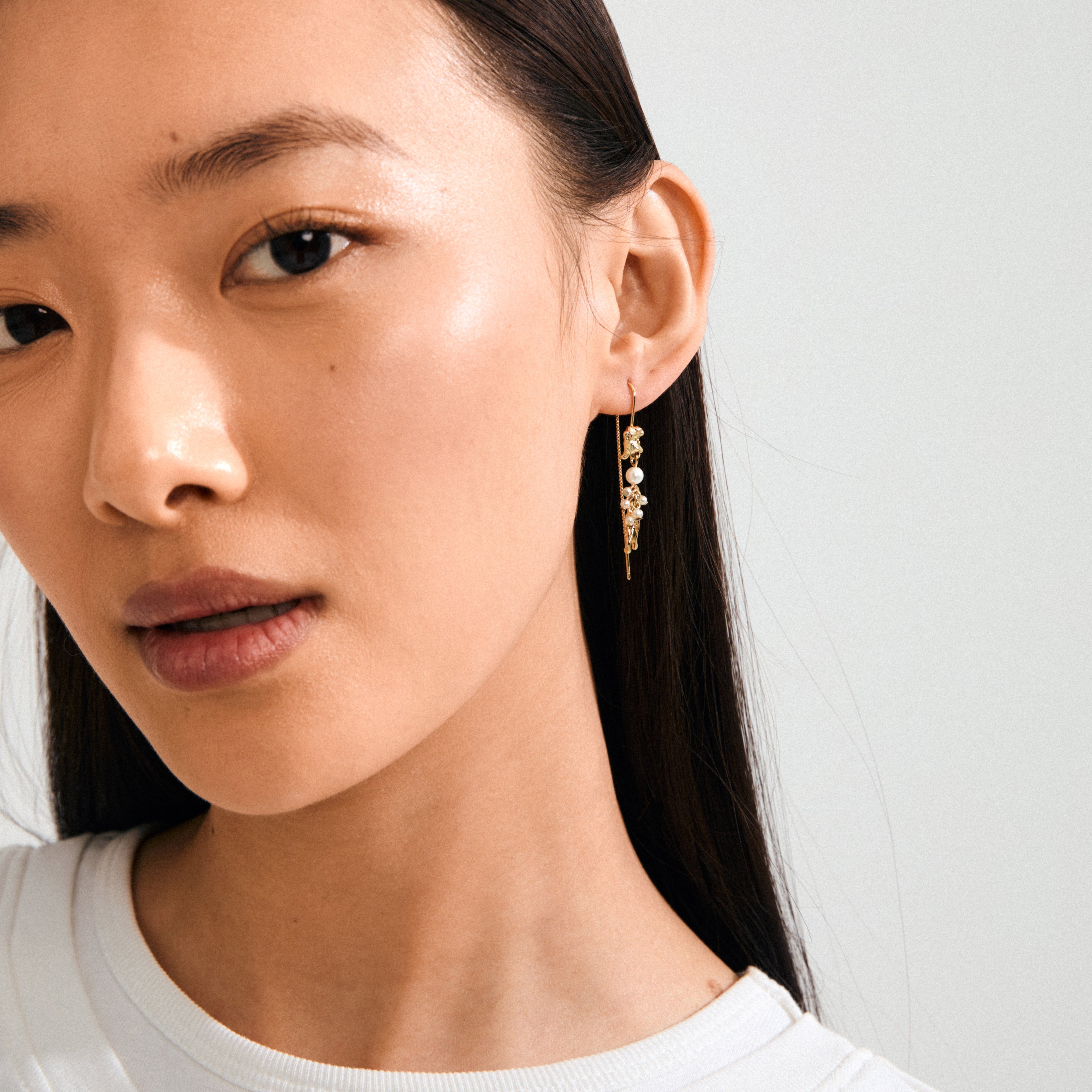 Profile of a woman showcasing Pilgrim's MILO chain earrings, gold-plated with pearl-toned beads and crystals, reflecting a whimsical, adventurous style.