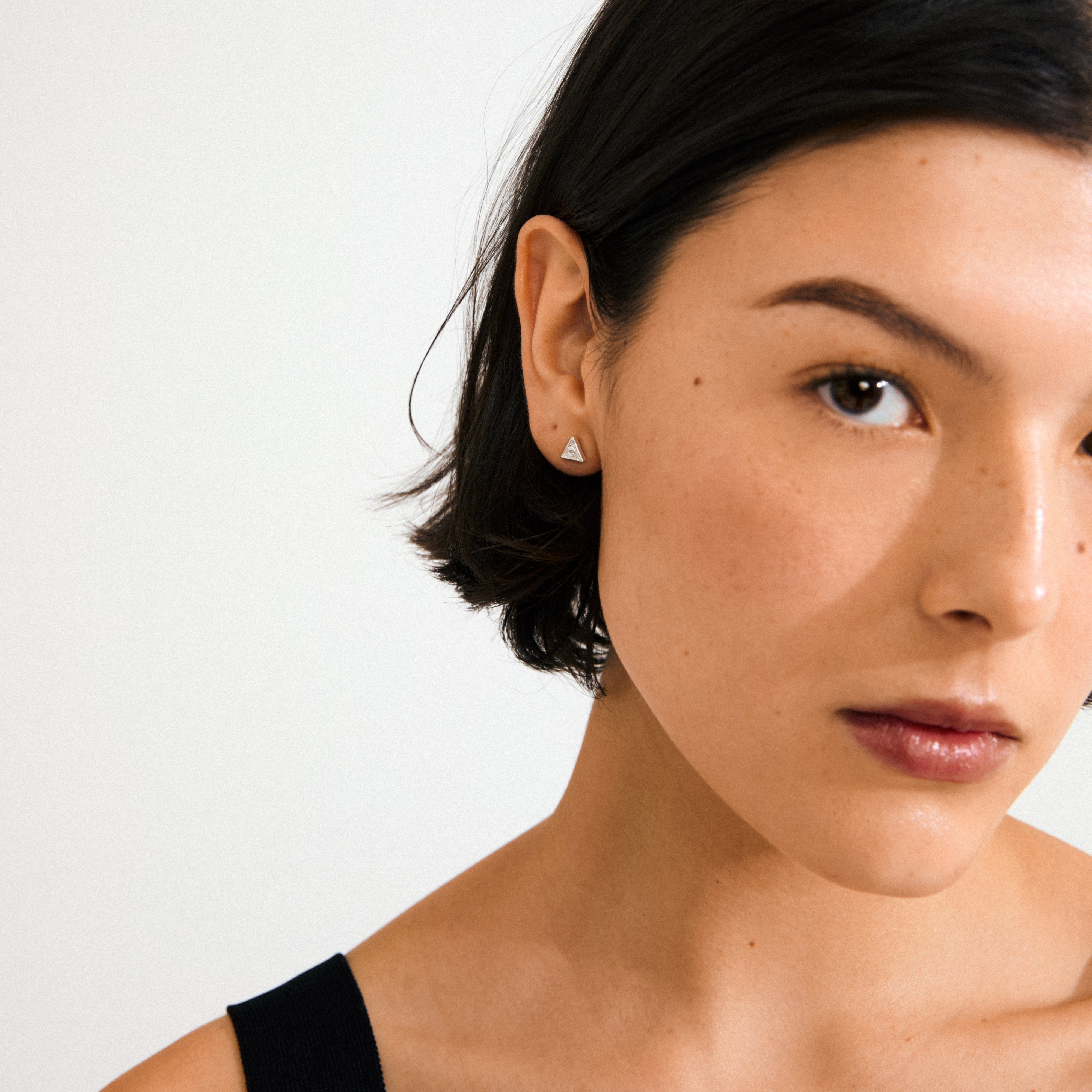 Young person wearing a sleeveless top and silver-plated RYLEE stud earring with a triangle design, adding a minimalist, boho-chic touch.