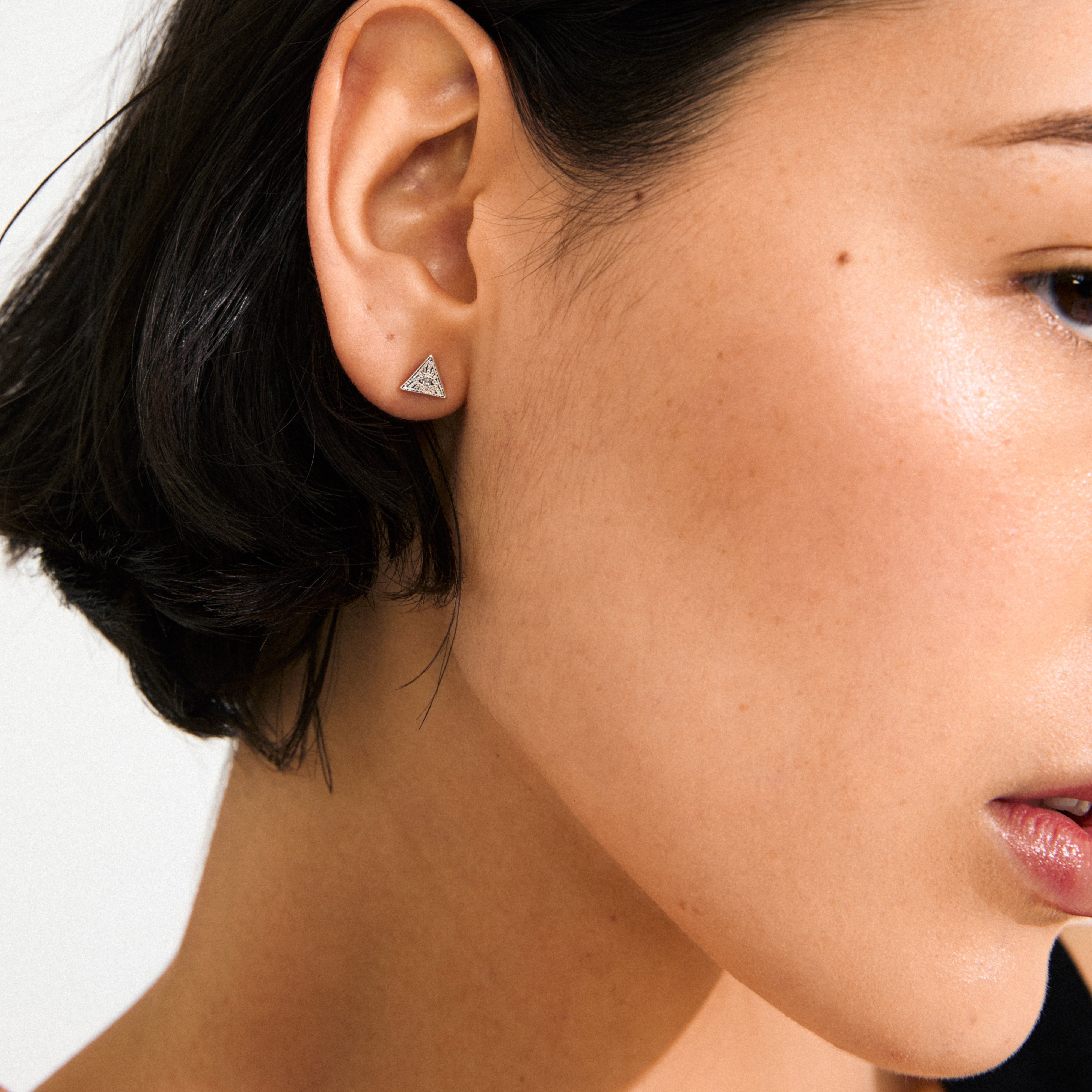 Close-up of a woman's ear wearing RYLEE earrings silver-plated, triangular studs with crystal accents, reflecting Pilgrim's boho-chic style.