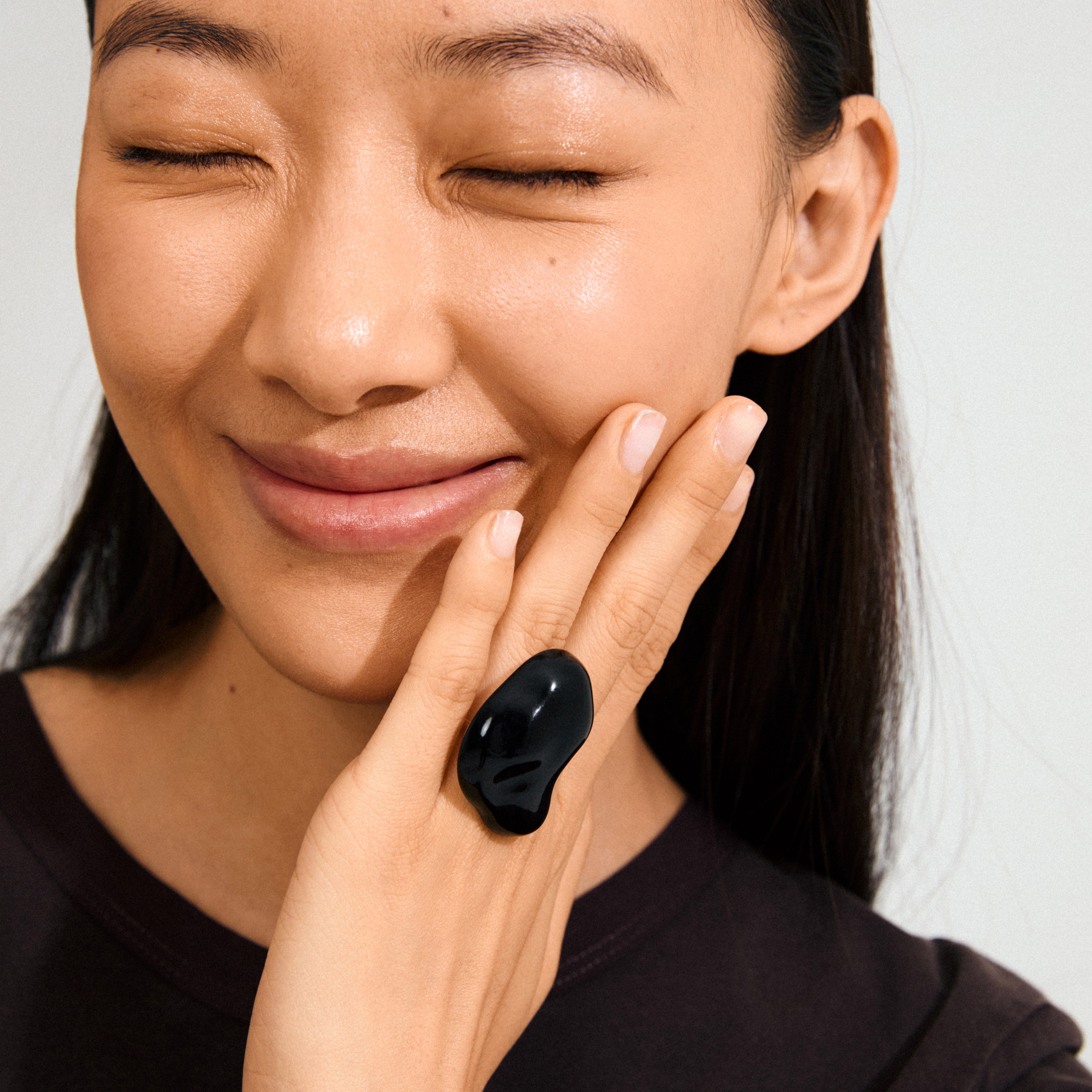 Young woman wearing the LIAN ring silver-plated/black, showcasing its chunky, organic black acrylic design on her hand, embodying Pilgrim's trendy, sustainable style.