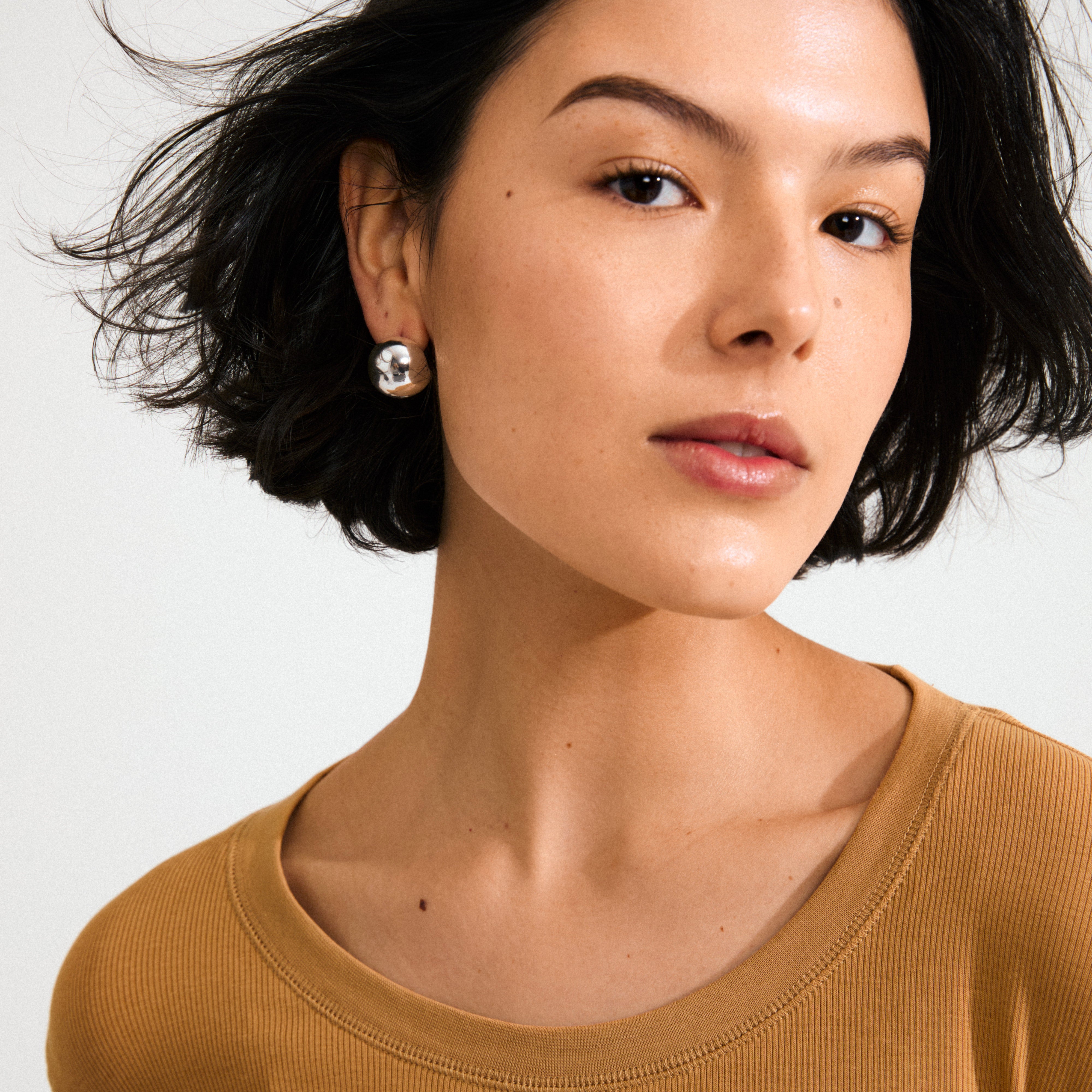 Young woman wearing Pilgrim's JACE silver-plated stud earring, featuring a reflective bubble dome design, highlighting vintage-inspired style with a sustainable twist.