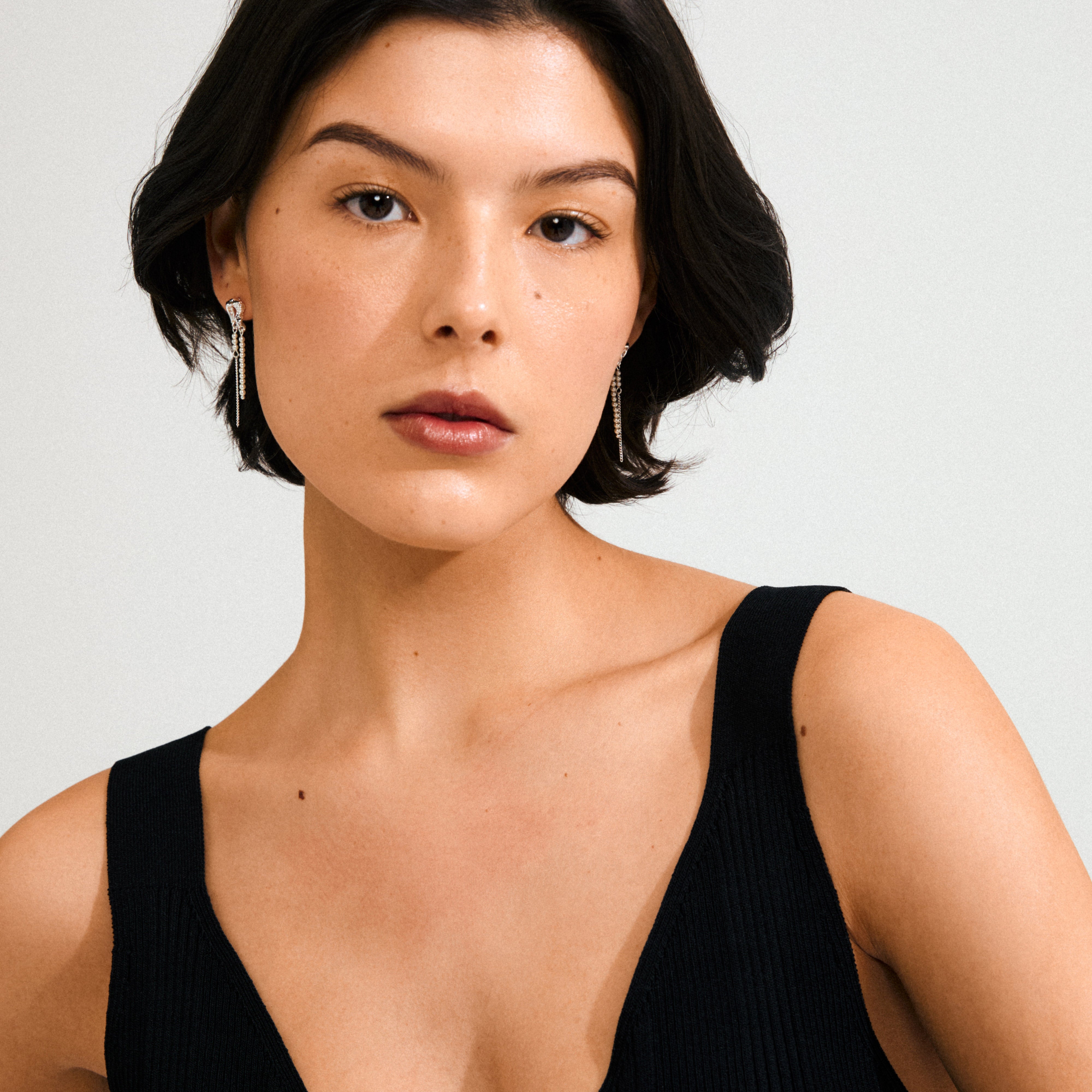Young woman wearing Pilgrim's VINCENT earrings, silver-plated with pearl-toned beads, highlighting their delicate, fairytale-inspired charm against her short dark hair.
