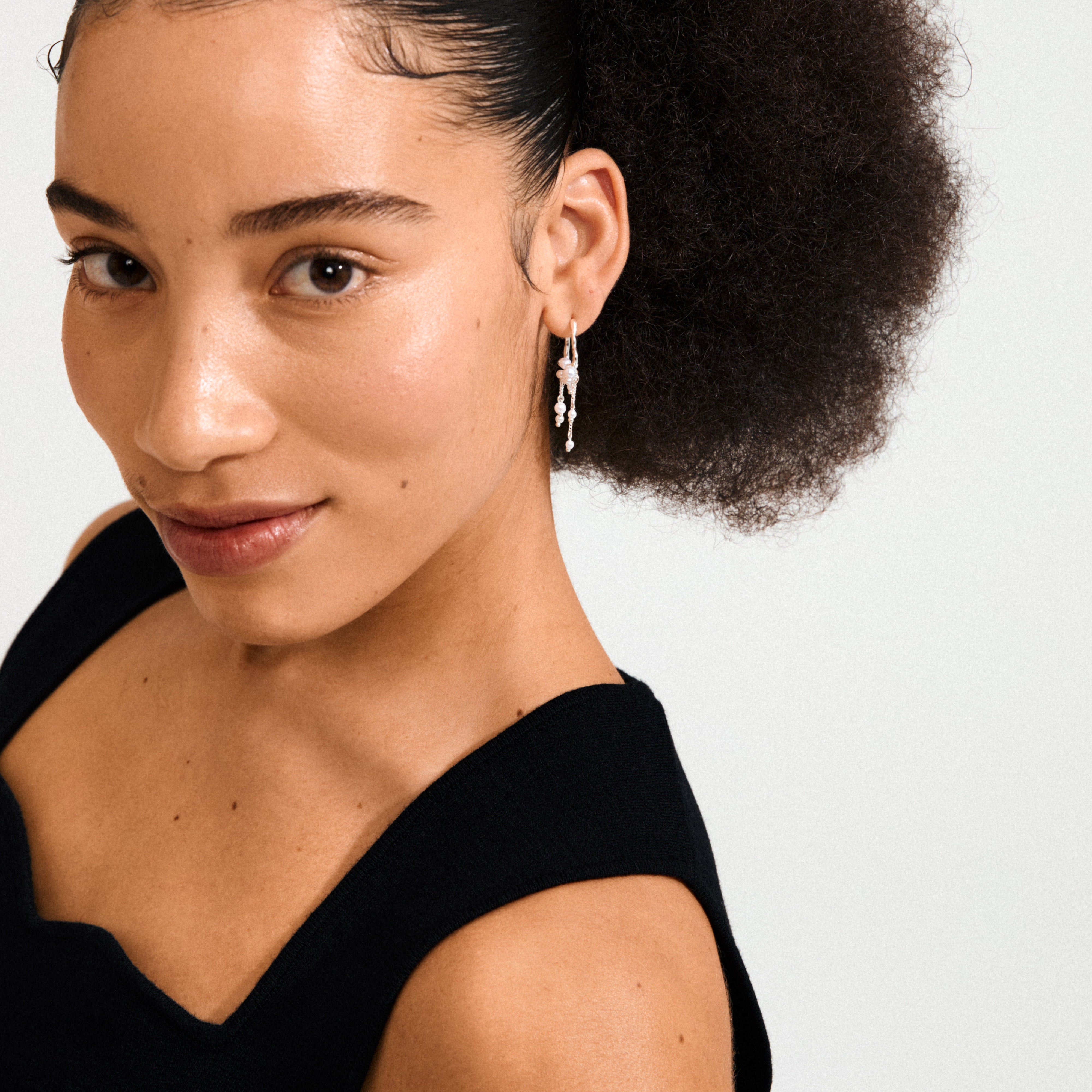 Young woman wearing Pilgrim's JASPER silver-plated earrings, featuring a dreamcatcher-inspired design with dangling beads and chains, exuding a boho-chic vibe.