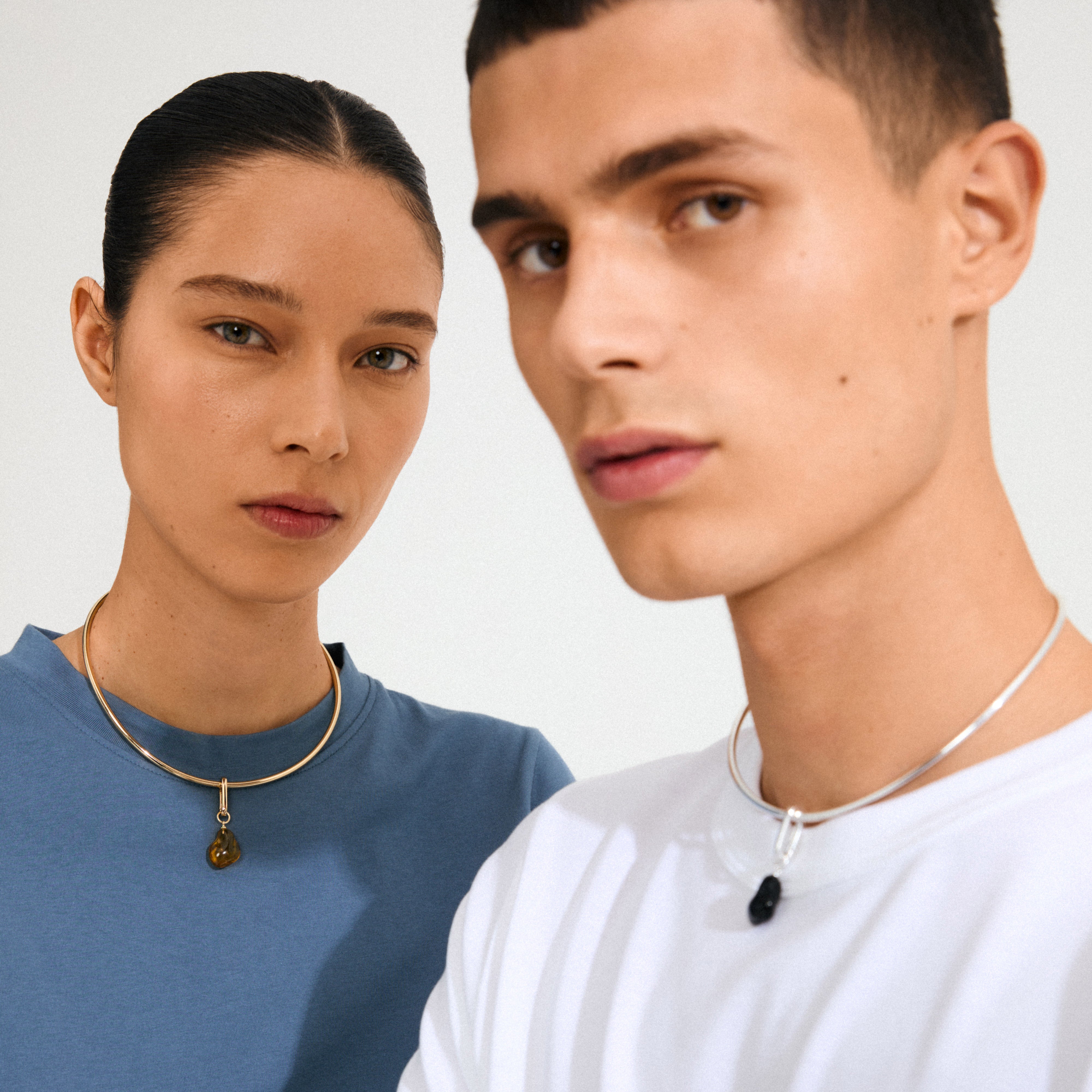 Two models wear Pilgrim's CHARM mold pendant, silver-plated, featuring irregular stone pendants, showcasing a blend of simplicity and bohemian style.